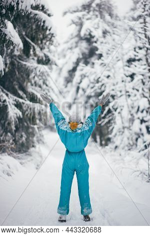 Woman In Ski Suit In Snowy Forest During Winter Vacations Outdoors