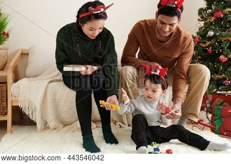 Prents Playing With Little Son At Home On Christmas Eve