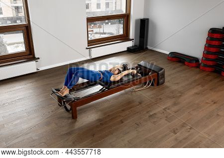 The Instructor Does Exercises On The Reformer, A Beautiful Girl Trains On The Modern Reformer Simula
