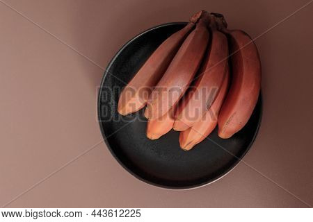 Bunch Of Ripe Organic Red Bananas On Beige Table. Fruit Background. Musa Acuminata Red Dacca. Contai