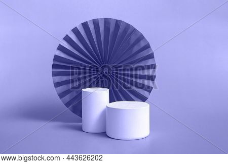 White Cylindrical Podium With Red, Green Paper Fan Background For Branding And Product Presentation.
