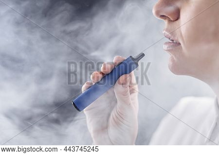 Caucasian Woman Smokes A Disposable Vape In The Studio.