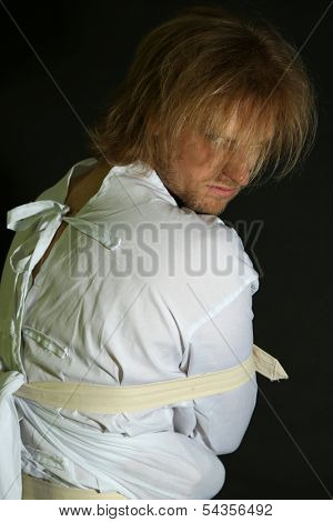 Mentally ill man in strait-jacket on black background