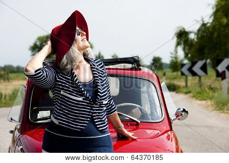 Happy senior woman with vintage car