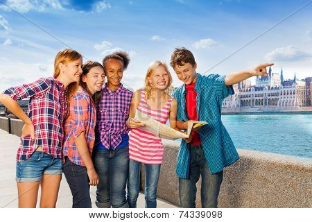Kids with map standing together on embankment