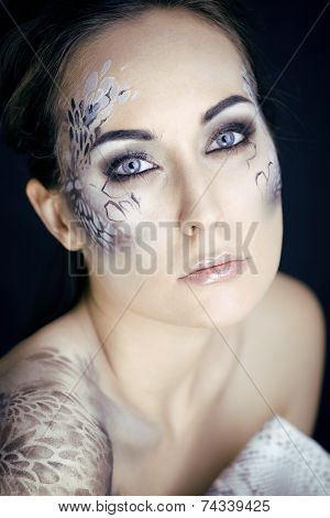 fashion portrait of pretty young woman with creative make up like a snake, victim with python skin c