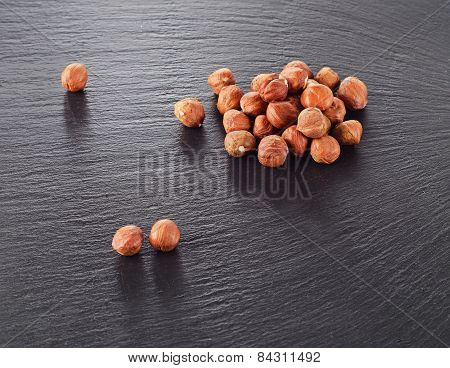 Heap Of Hazelnuts On A Dark Stone Background