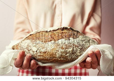 Woman holding tasty fresh bread, close up
