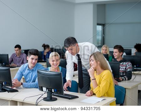 group of students with teacher in computer lab classrom learrning lessons,  get help and support