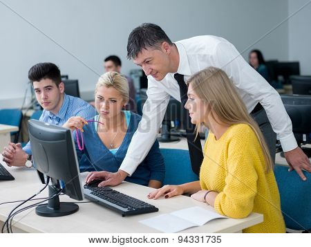 group of students with teacher in computer lab classrom learrning lessons,  get help and support