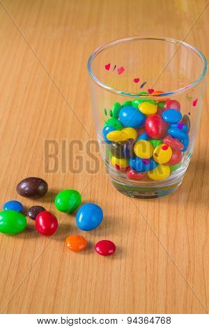 Colorful chocolate and milk into a glass placed on a wooden floor.