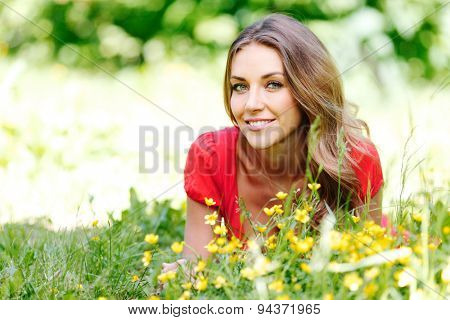 beautiful young woman in red dress lying on grass