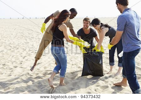 Group Of Volunteers Tidying Up Rubbish On Beach