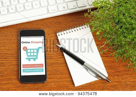 Smart phone with online shopping concept keyboard notepad pen and green plant