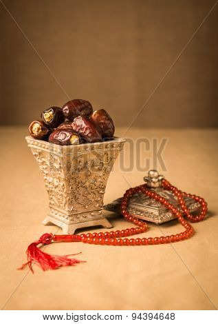 Ramadhan objects. Ripen dates in a decorative Islamic jar and prayer beads.