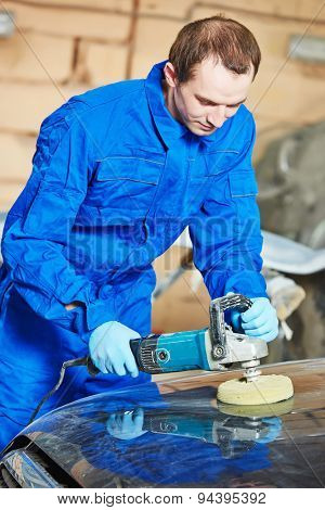 mechanic polishing car body at automobile repair and renew service station shop by power buffer machine