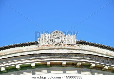 Hammer and Sickle in conjunction with the emblem of the USSR of the concrete on the roof of the old building .