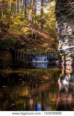 Serene waterfall reflects in the calm water and gorge at Raymondskill Falls near Milford, PA, in fall, portrait
