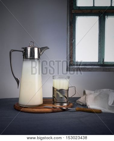 ancient jug with milk and a glass on a wooden table