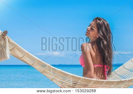 Young woman swinging in hummock on blue sea background