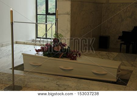White coffin with funeral flowers in a crematorium