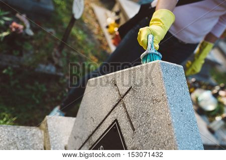 Woman Cleans A Grave With Brush