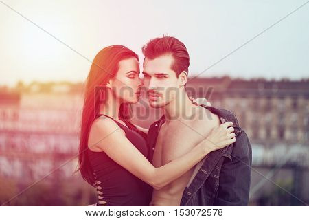 Sensual young couple posing outdoor brunette woman seduce man in sunset whispering