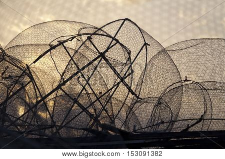 Silhouette of old fishing nets against sunrise sky