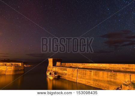 Craster Harbour at Night, with stars above on the Northumberland Coast, with just a hint of the Aurora Borealis