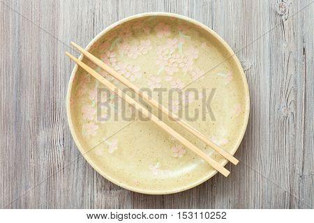 Top View Of Yellow Plate With Chopsticks On Gray