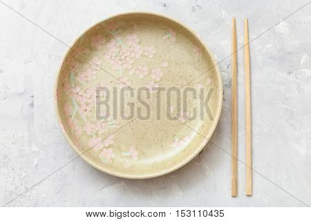 Above View Yellow Plate And Chopsticks On Concrete