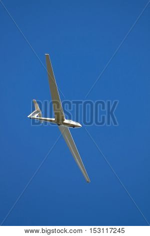 A sailplane in front of a blue sky glides through the air without its own motor drive.