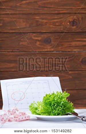 Diet concept. Fresh salat, and measurement tape - diet and healthy eating concept. Starting new life from monday. On a wooden background
