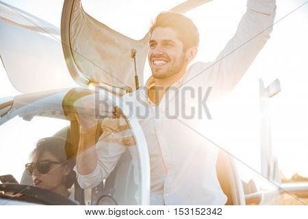 Cheerful young man pilot getting out of the plane after landing