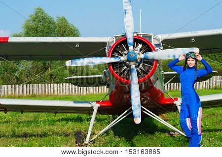 woman pilot in helmet standing with airplane