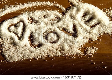 heart and love letters written in sugar on a wooden background in sunlight. declaration of love