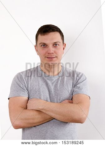 Happy young man. Portrait of handsome young man in casual shirt keeping arms crossed and smiling while standing against white background