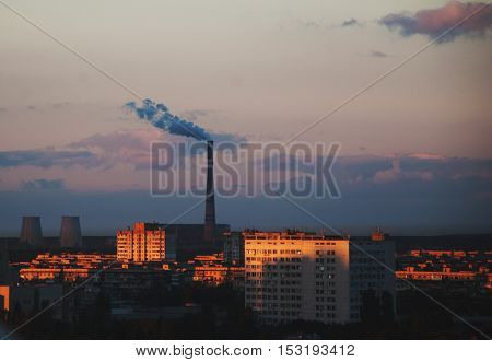 Urban landscape at sunset. Smoke from the chimney of CHP