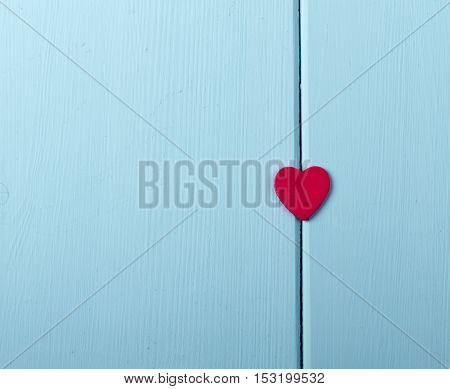 Red wood heart hanging on painted rustic wooden background