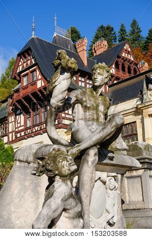 Statue in front of beautiful Peles castle and ornamental garden in Sinaia, Romania, between Valachia and Transylvania