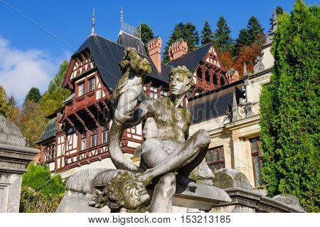 Statue in front of beautiful Peles castle and ornamental garden in Sinaia, Romania, between Valachia and Transylvania