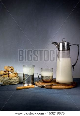 Milk from a jug pouring into glass on old wooden table. space for text