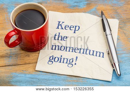 Keep the momentum going - handwriting on a napkin with a cup of espresso coffee