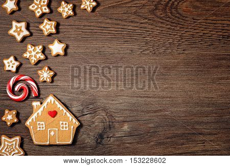 Gingerbread House Cookie with Candy cane and stars over a wooden background.