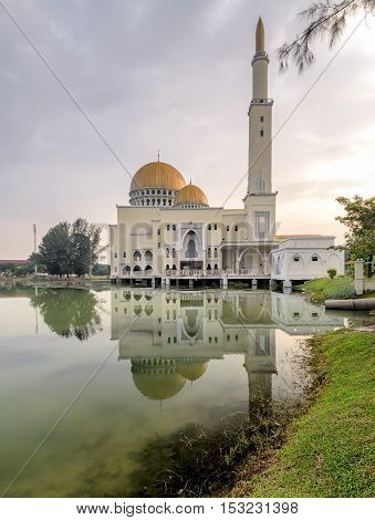 View and reflection of Assalam Mosque with blue skies and white clouds.