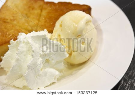 honey toast is ice cream with whipped cream and bread topped with honey in white dish on the wood table whipped cream focus
