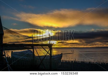 Old stranded boat in the sunrise at the Ytrebyfjaera (city shoreline) in Vadso, Norway