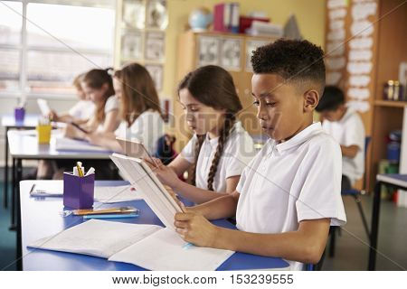 Kids use tablet computers in primary school class, close up