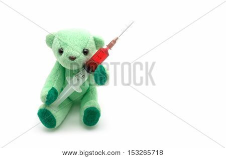 Small green teddy bear holding red injection syringe on white background children medical concept