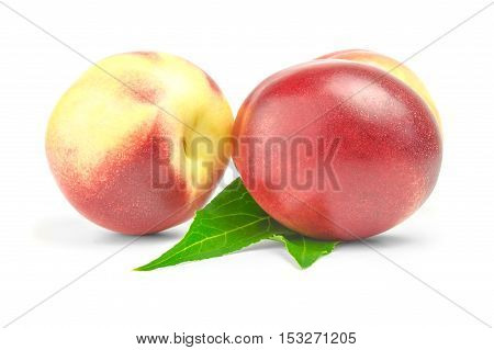 two ripe nectarines with green leaves over white background.